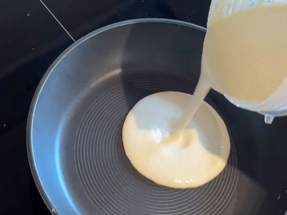 Pouring crepe batter into a frying pan