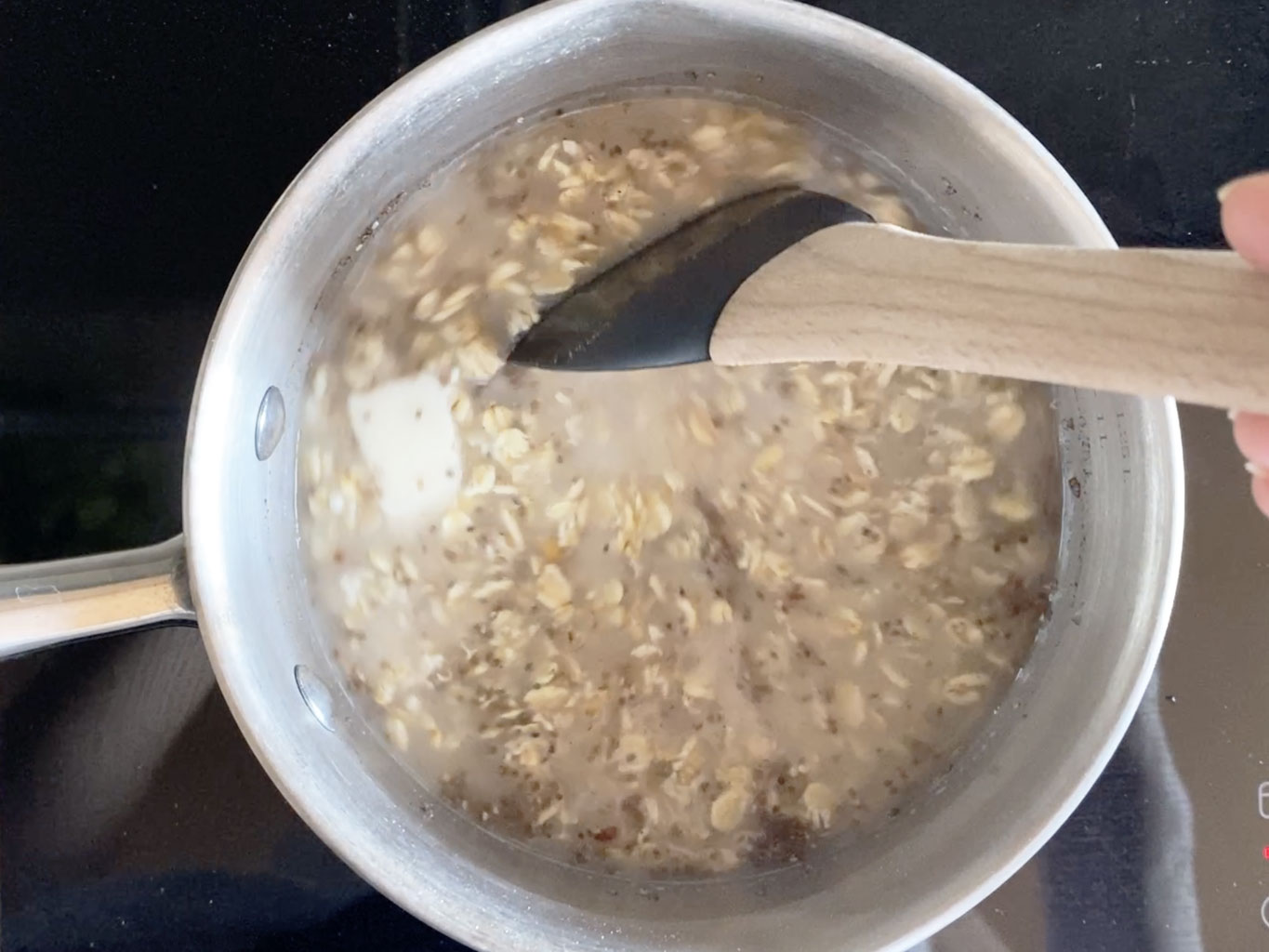 Stirring oatmeal in a stainless steel saucepan