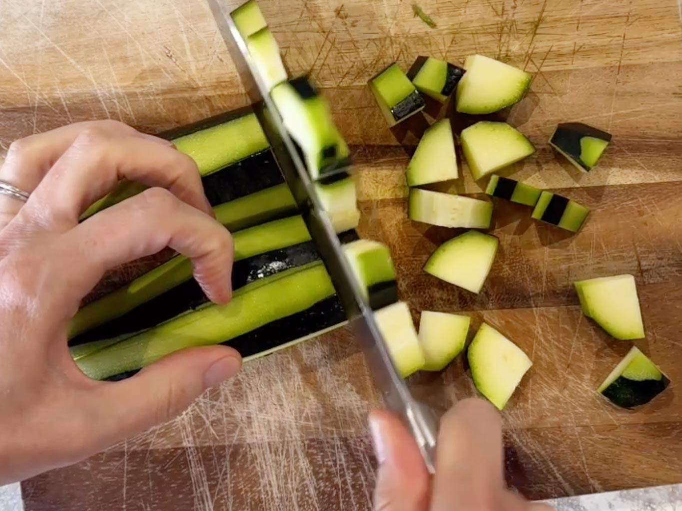 Chopping zuchinni on a wooden cutting board