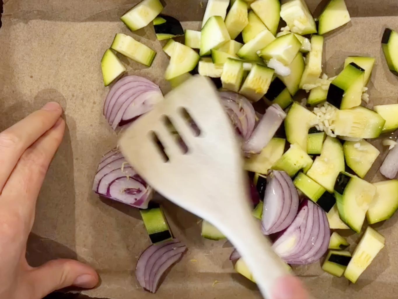 Stir zucchini, red onion, fresh garlic, lemon zest and coconut oil in a baking tray
